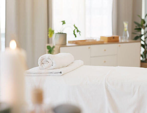 room in a spa with a massage table with clean folded linens on it