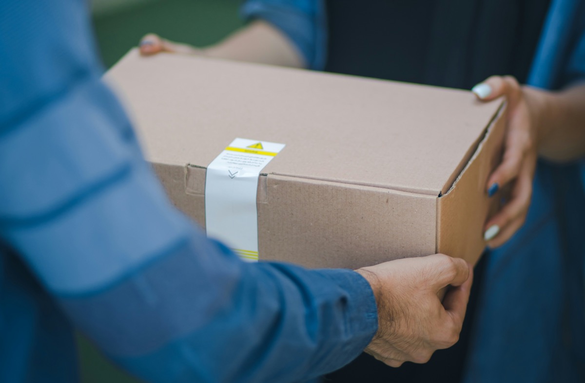 Woman hands a package to an employee ready for it to be shipped from a franchise printing and shipping store.