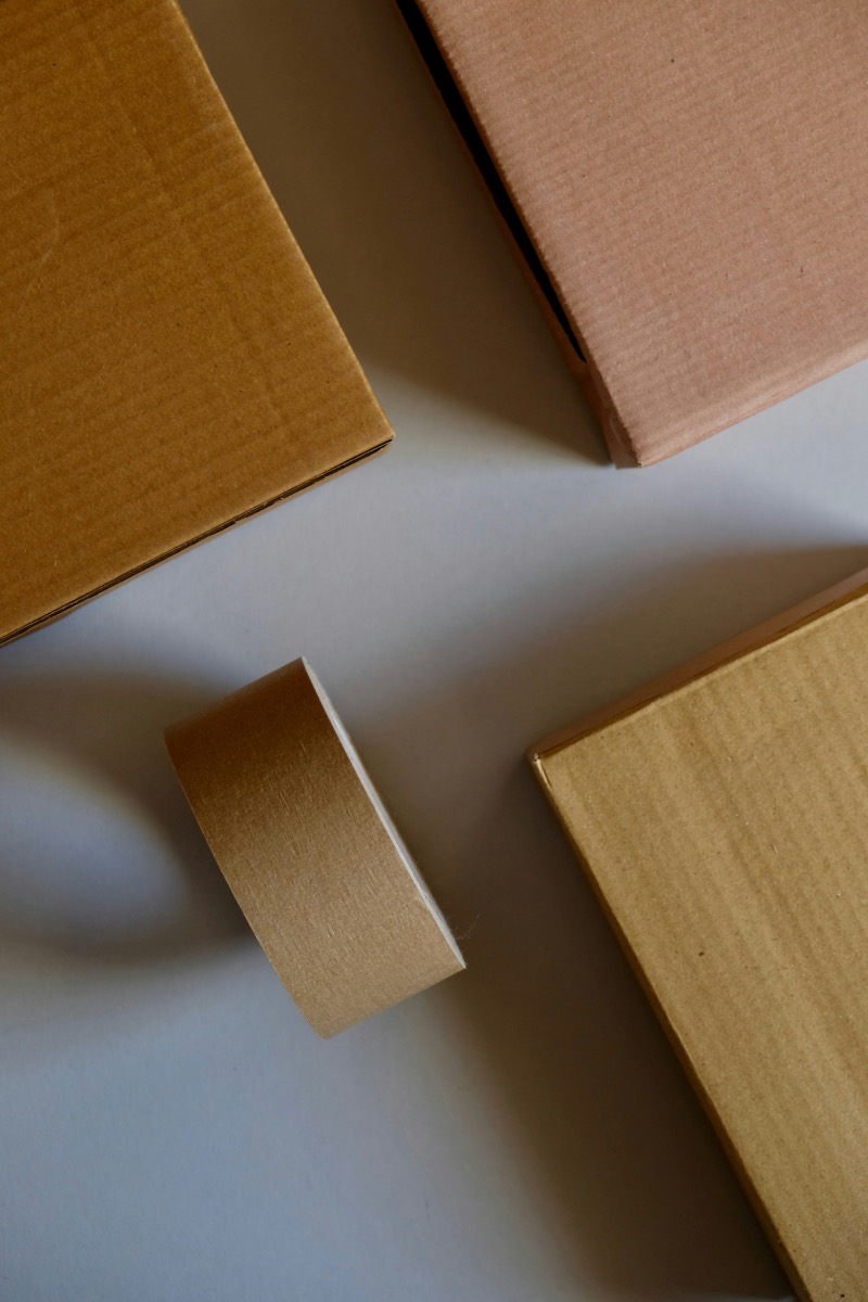 Packages lay on a desk artfully casting shadows waiting to be taped up.
