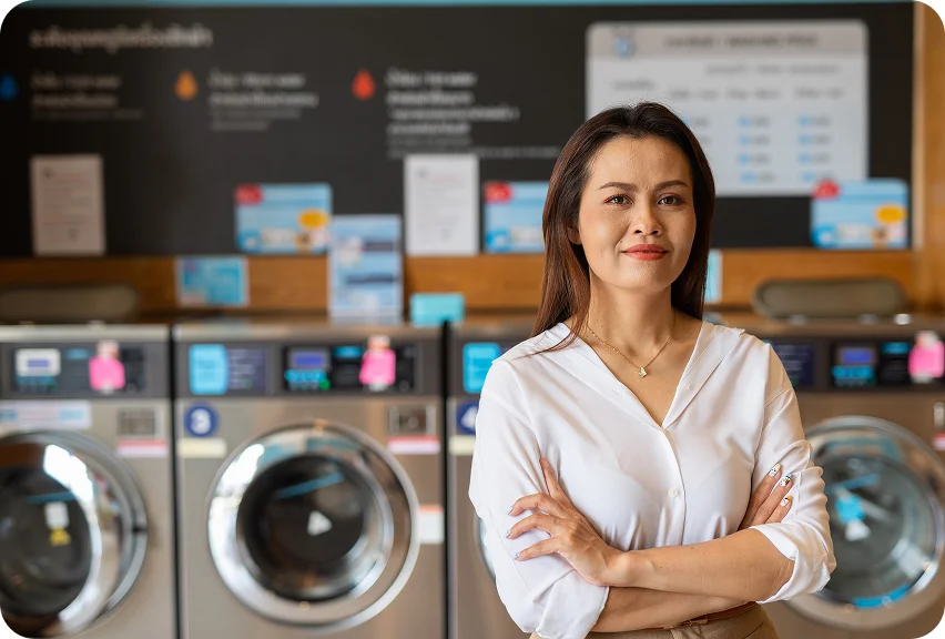Woman standing with arms crossed in front of washing machines in a laundromat
